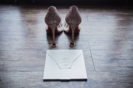 shoes of the bride with wedding rings on floor