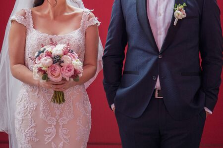 bride and groom stand next to red wallの写真素材