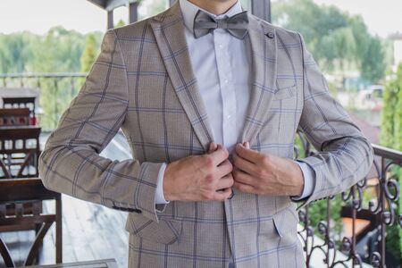 man puts on suit on the verandaの写真素材