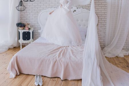 the bride in a peignoir holds wedding dressの写真素材