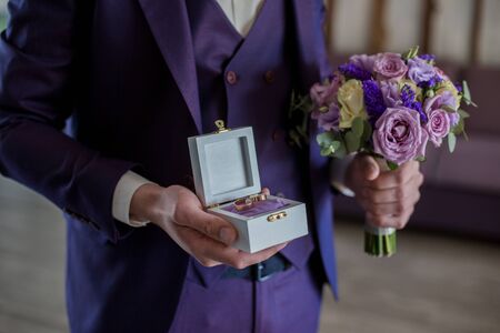 the groom holds box with wedding rings in hands
