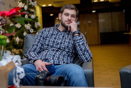 a man sits in a chair with phone in his handsの写真素材