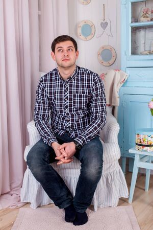 a man in plaid shirt in an armchairの写真素材