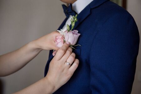 bride puts on buttonhole to the groomの写真素材