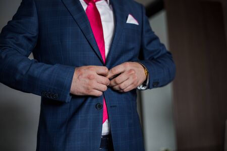 man fastens the button of suit jacket