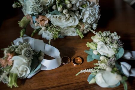 gold wedding rings near bride's bouquetの写真素材