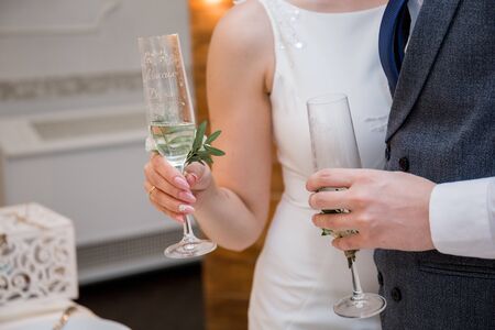 wedding glasses in hands of bride and groomの写真素材