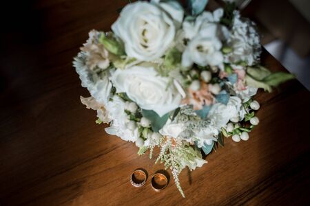 gold wedding rings near bride's bouquetの写真素材