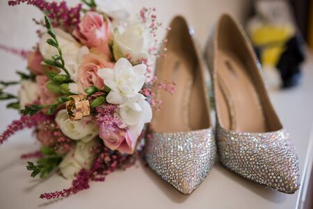 a wedding gold rings with bride shoes and decorの写真素材