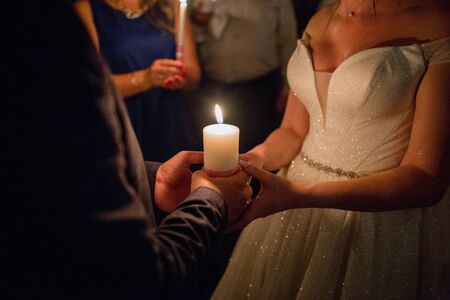 newlyweds are holding candle in their handsの写真素材