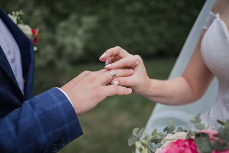 the bridegroom puts ring on the brideâs fingerの写真素材