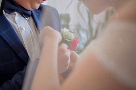 bride puts on buttonhole to the groomの写真素材