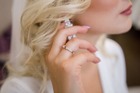 bride puts on beautiful earrings in ear