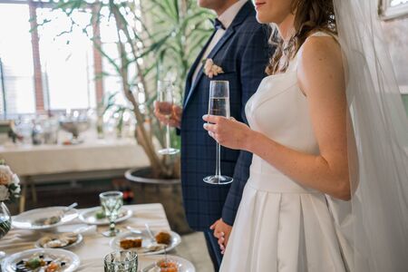 the bride and groom hold glasses at the weddingの写真素材