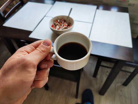 cup of coffee in man hand in the kitchenの写真素材