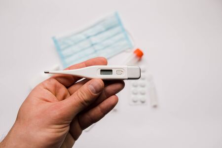 electronic thermometer in hand with a medical maskの写真素材