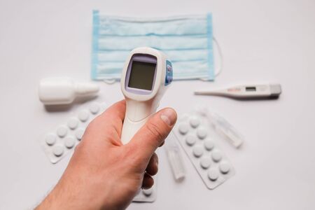 electronic thermometer in hand with a medical maskの写真素材