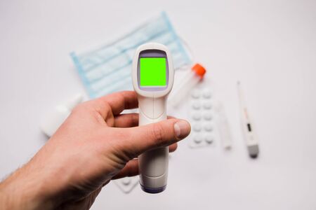 electronic thermometer in hand with a medical maskの写真素材
