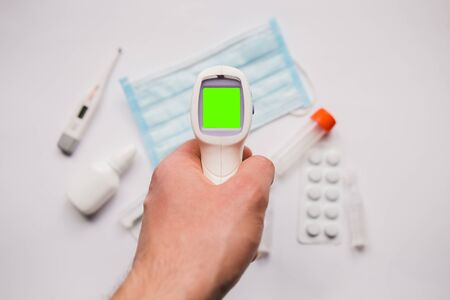 electronic thermometer in hand with a medical maskの写真素材