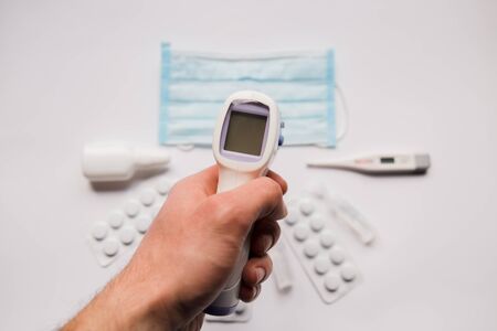 electronic thermometer in hand with a medical maskの写真素材