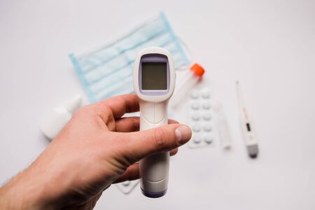 electronic thermometer in hand with a medical maskの写真素材
