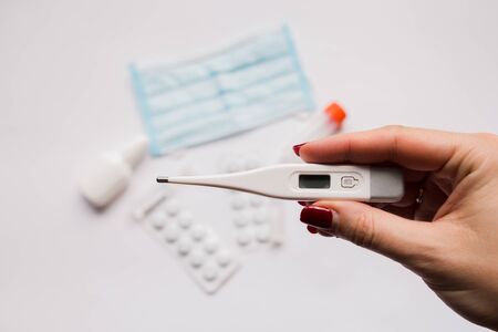electronic thermometer in hand with a medical maskの写真素材