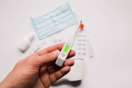 electronic thermometer in hand with a medical maskの写真素材