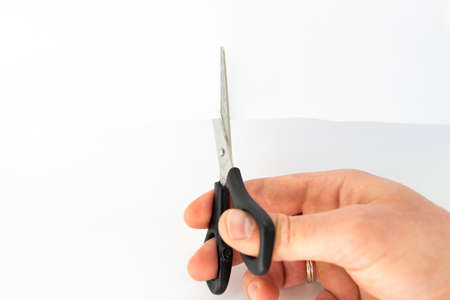 scissors in the hands of a man and white sheetの写真素材