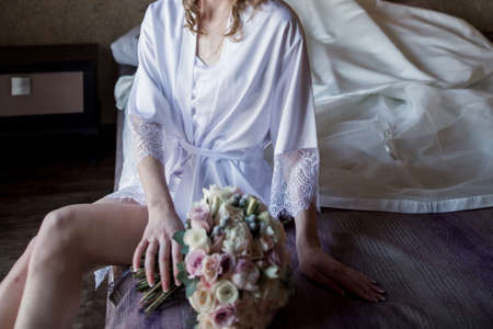 the bride in a negligee sits on the bed in morningの写真素材