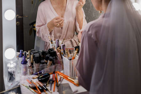 bride in peignoir near makeup table