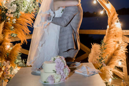 a bride and groom near wedding arch with cakeの写真素材