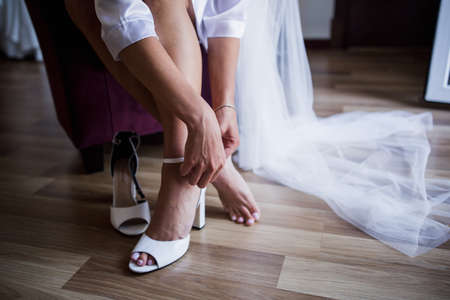 the bride puts on her shoes in morningの写真素材