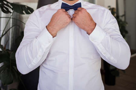 a man in a suit puts on bow tieの写真素材