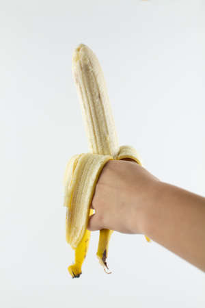 a ripe peeled banana in hand on white backgroundの写真素材