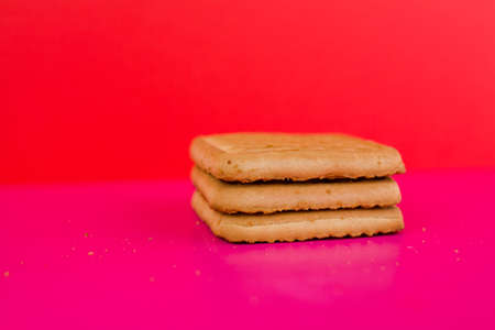 a square cookies on a pink background on the tableの写真素材