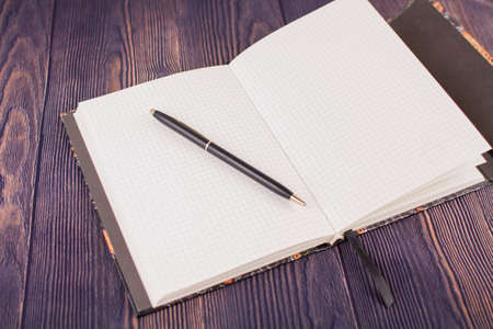 a notebook with pen on wooden table