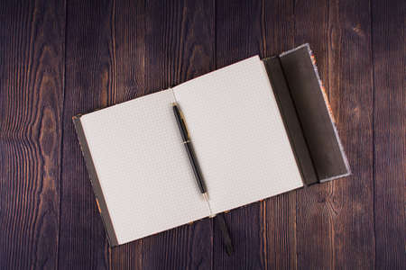 a notebook with pen on wooden tableの写真素材