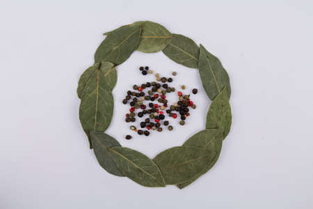 a bay leaf with peppercorns on a white background