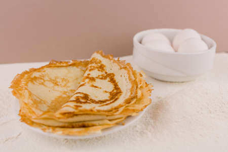 a beautiful round thin pancakes on the kitchen table with flour and whisk and eggsの写真素材