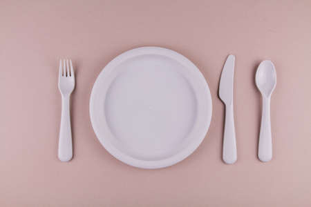 set of plastic dishes spoon fork knife gray plate on the table