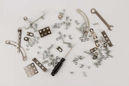 a children's iron constructor with nuts and screws and a screwdriver on a white backgroundの写真素材
