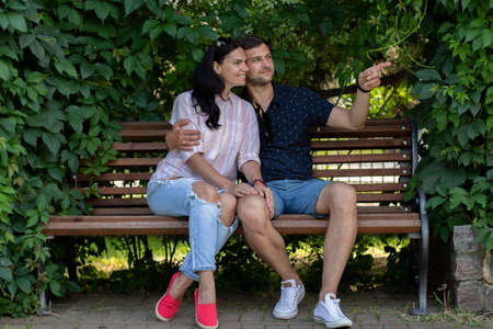 guy with a girl sitting on a bench in the park in summerの写真素材