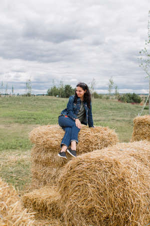a girl on sheaves of hay in summer with dark hair beautiful