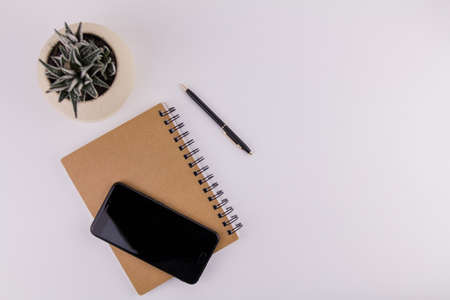 a workplace on white background with notepad smartphone flower and pen