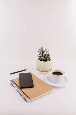 a workplace on white background with notepad smartphone flower and pen and cup of coffeeの写真素材