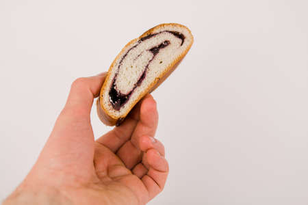 a butter bun with poppy seeds on a white plate in a man's handの写真素材