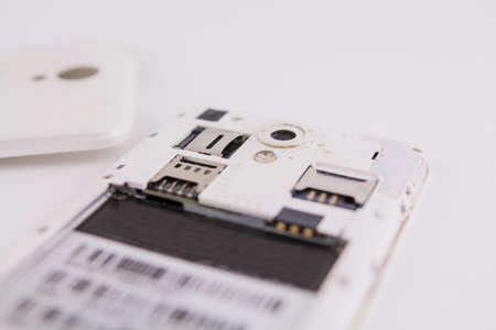 a smartphone with removed cover and battery on white background phone repairの写真素材