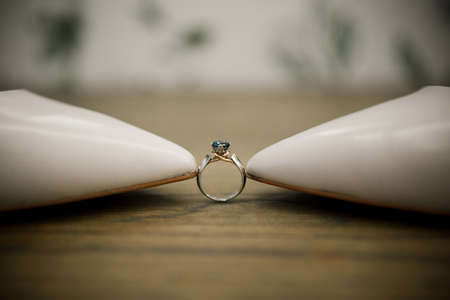 a wedding engagement ring between bride's shoesの写真素材