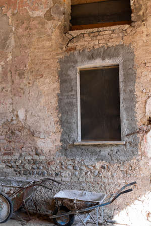 a window in a house with bricks and a trolley for repairsの写真素材