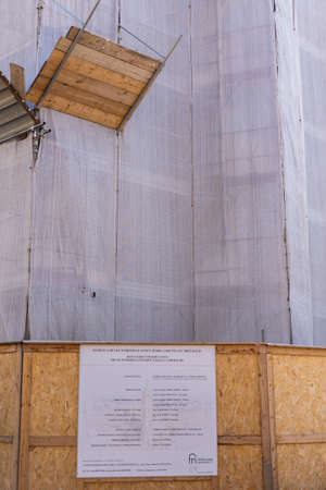 a building at a construction site covered with fabric and scaffolding in the cityの写真素材